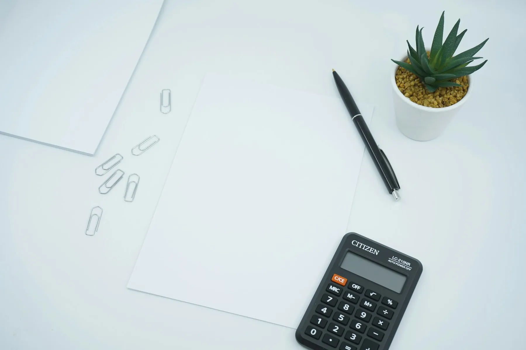 A calculator beside a pen on printer paper