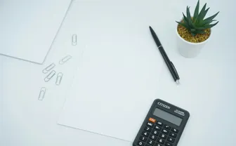 A calculator beside a pen on printer paper