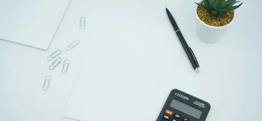A calculator beside a pen on printer paper