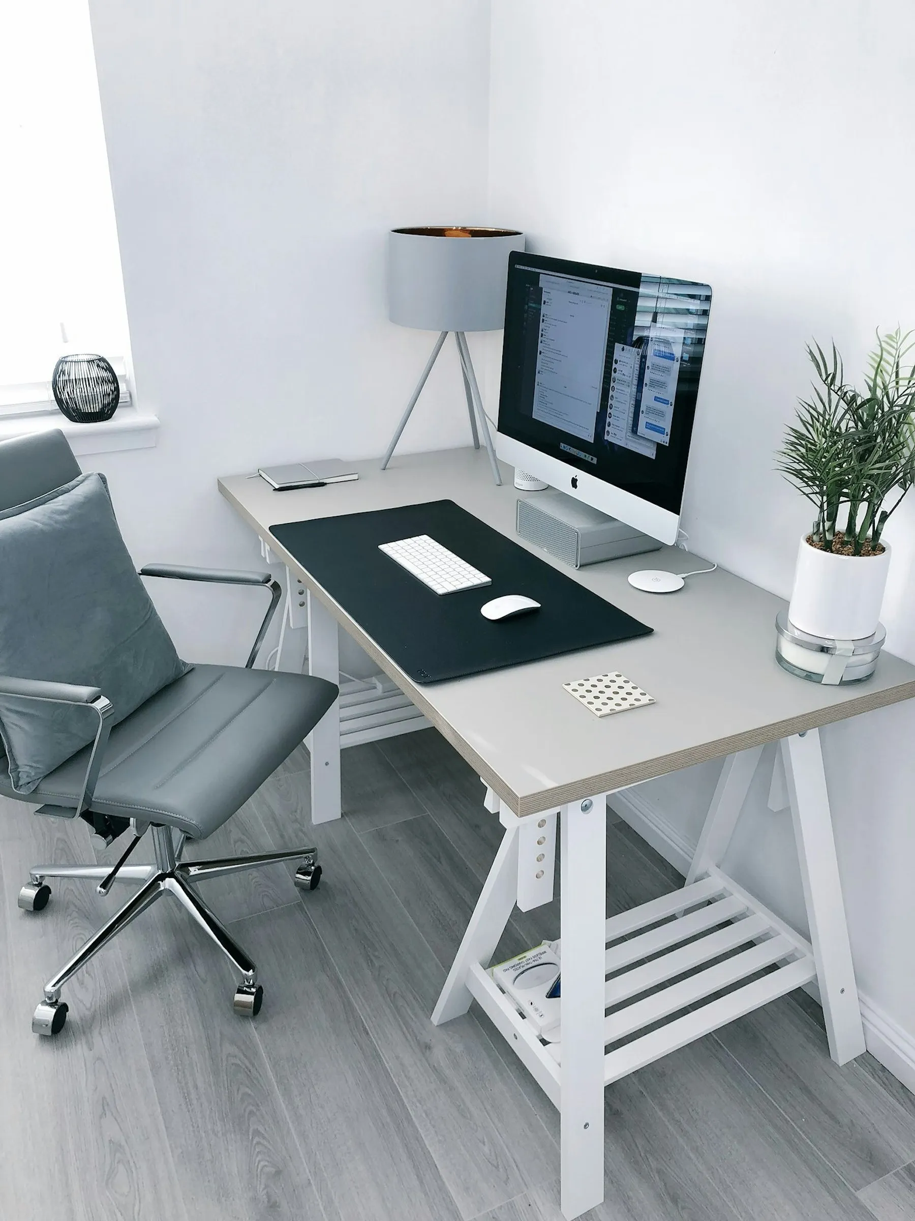 An office chair beside a desk with a monitor and plant