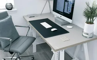 An office chair beside a desk with a monitor and plant