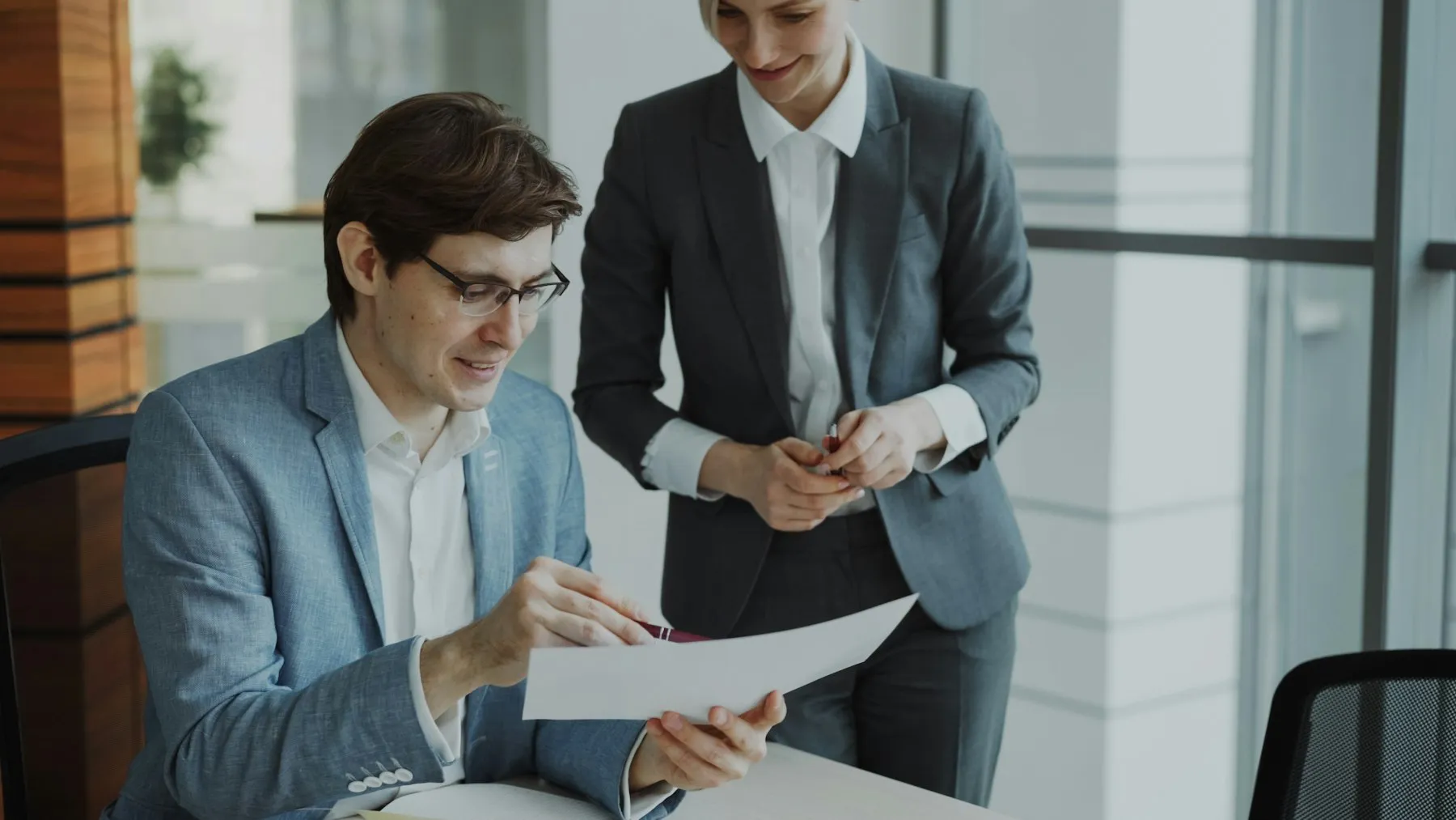 Two colleagues reviewing a document together in a modern office