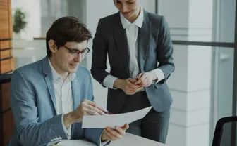 Two colleagues reviewing a document together in a modern office