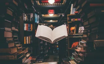 An open reference book among stacked books in a library