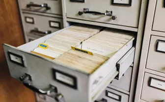 An open vintage file cabinet drawer filled with index cards