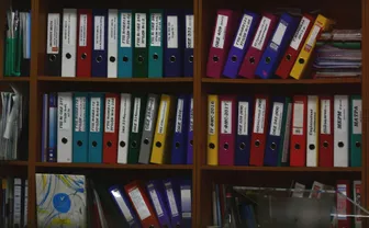 A shelf of distinctly colored ring binders
