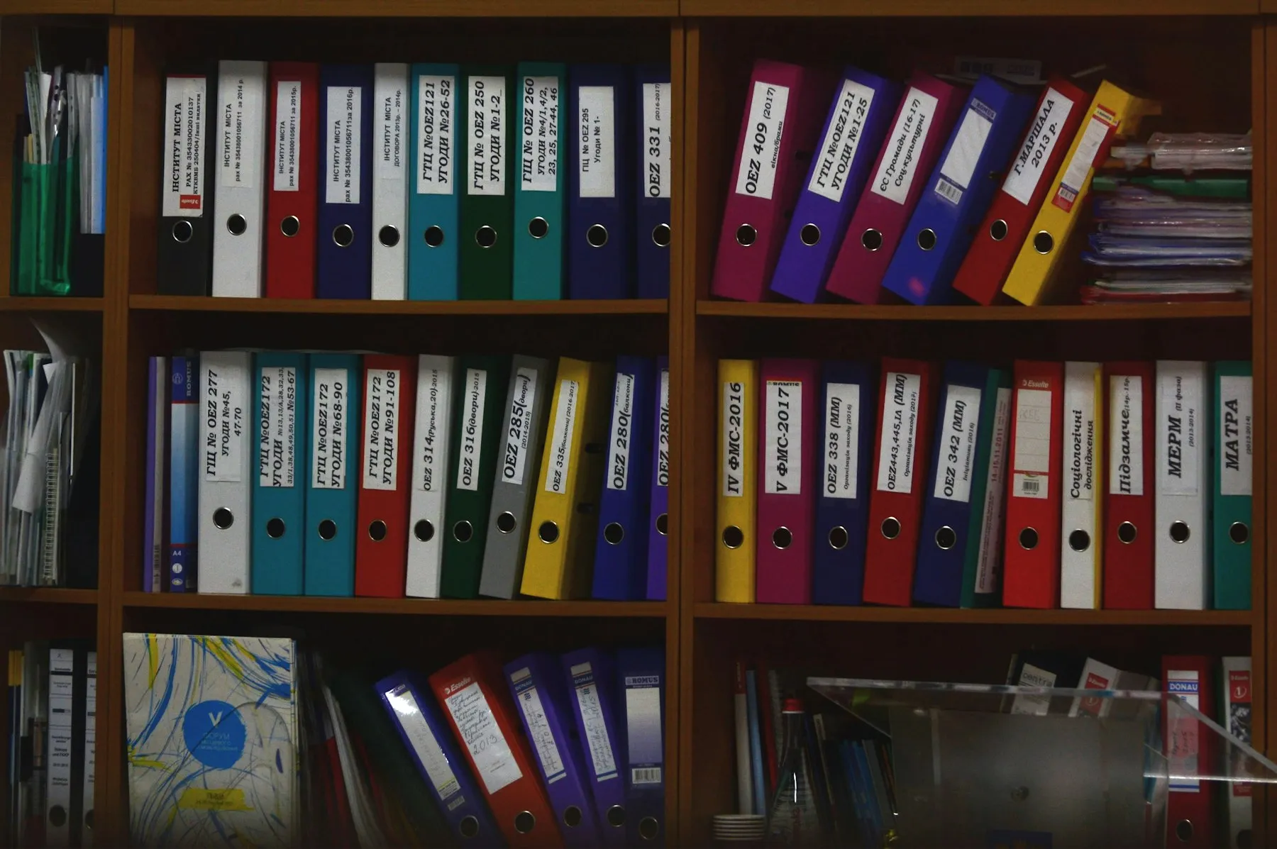 A shelf of distinctly colored ring binders