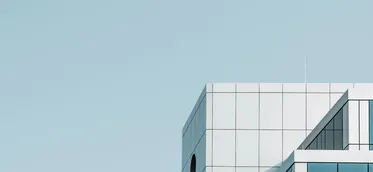 A modern glass office building against a blue sky