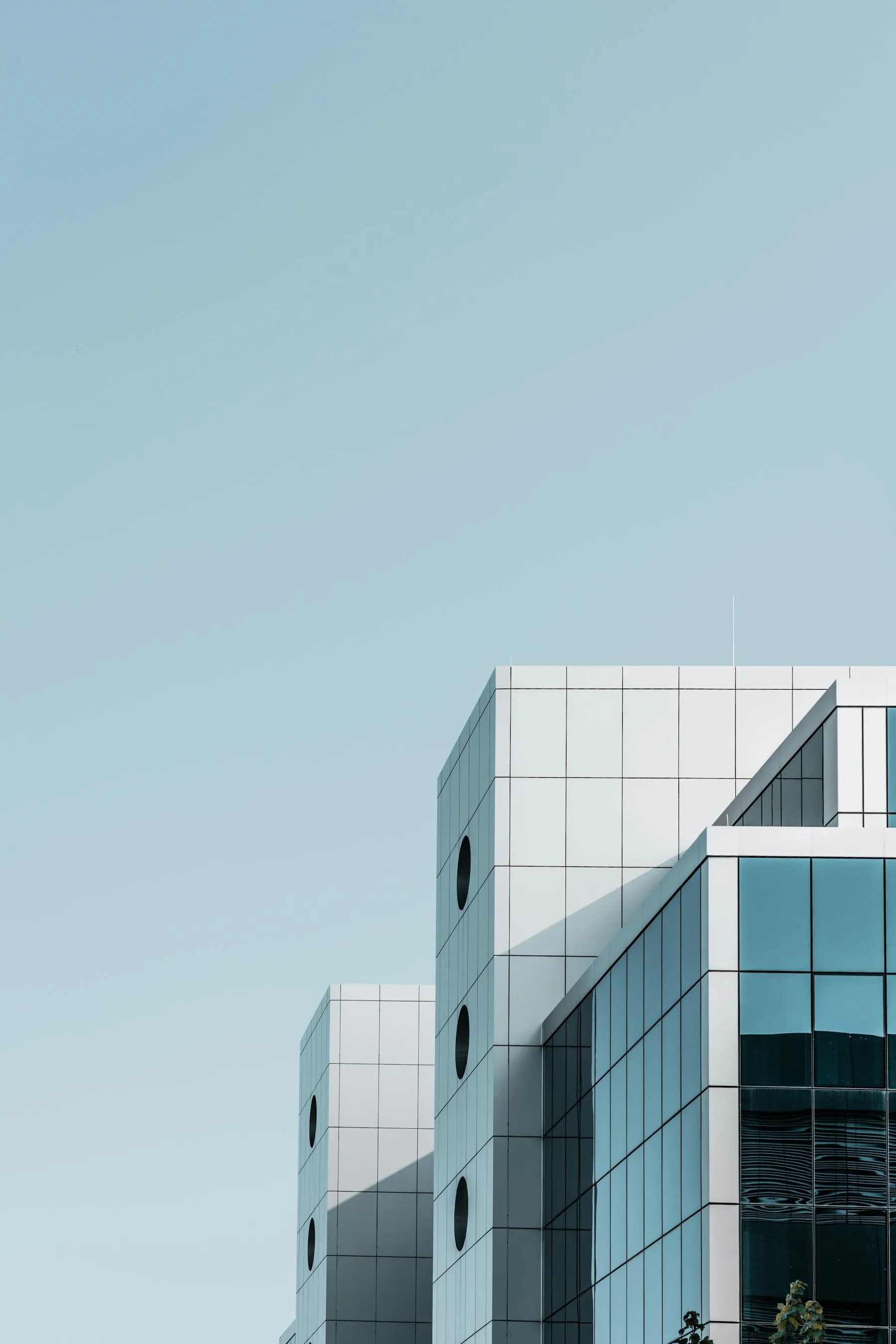 A modern glass office building against a blue sky