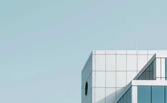 A modern glass office building against a blue sky