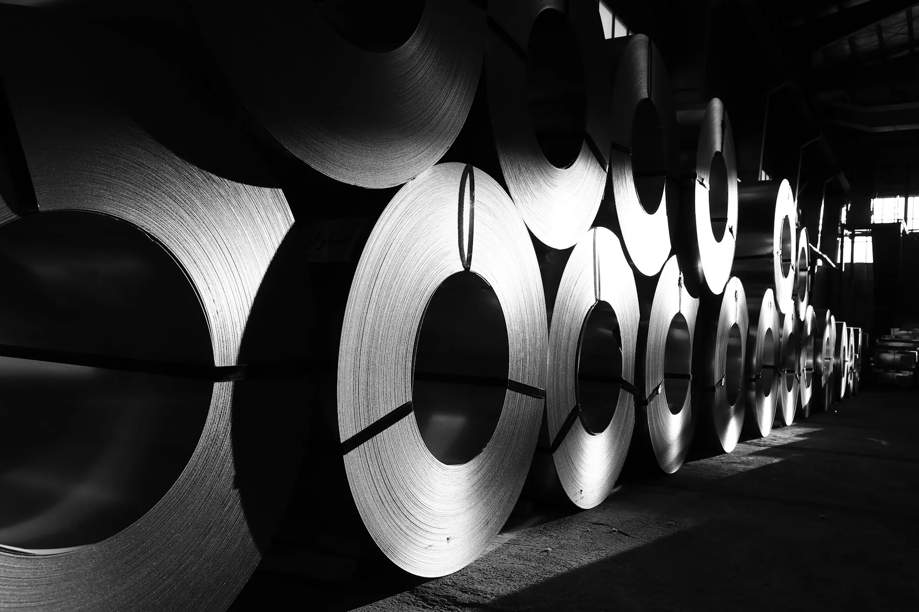 Rolls of steel lined up in a warehouse