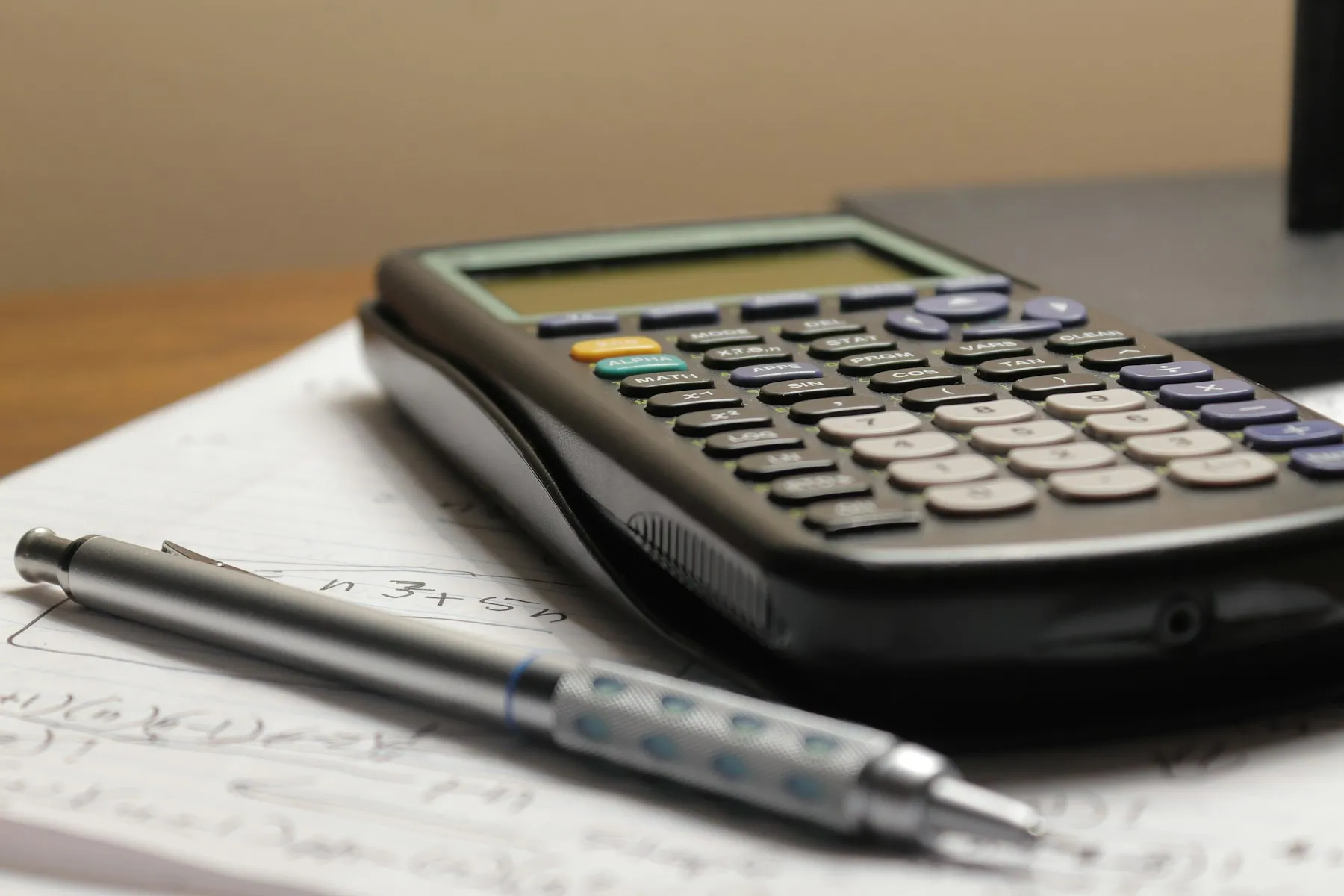 A calculator and pen resting on a sheet of math paper