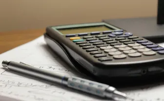 A calculator and pen resting on a sheet of math paper